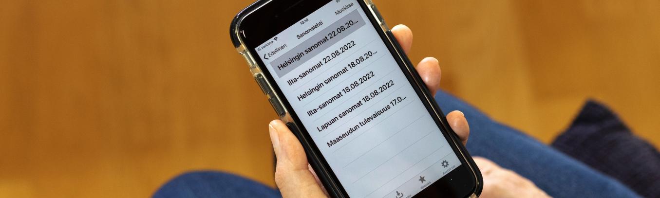 Kännykän ruudulla luettelo, jossa sanomalehtien nimiä.